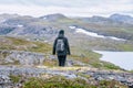 Mature woman walks down over high altitude Norwegian Mountains range terrain. Hiking high in Norwegian mountains.