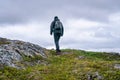 Mature woman walks up over high altitude Norwegian Mountains range terrain. Hiking high in Norwegian mountains. Healthy lifestyle