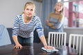 Mature woman watches as her daughter wipes the table