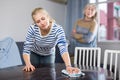 Mature woman watches as her daughter wipes the table