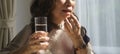 Mature woman woman holding pill and glass of water, taking daily vitamins or dietary supplements. Elderly healthcare, medication Royalty Free Stock Photo