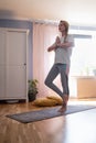 Mature woman working out indoors standing in Tree Pose. Royalty Free Stock Photo