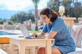 Mature woman working outdoors with headphones using laptop. Royalty Free Stock Photo