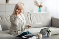 Mature woman working and talking on cellphone at home Royalty Free Stock Photo