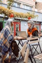 Mature women business partners with laptop discuss project on outdoors cafe terrace Royalty Free Stock Photo