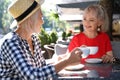 Mature women with cups of coffee talking at table in open cafe on sunny day Royalty Free Stock Photo