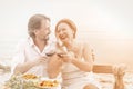 Mature woman and man happy together. Loving couple look each other embracing and drink red wine dating at beach cafe Royalty Free Stock Photo