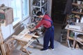 Mature working man using circular saw at carpentry shop