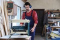 Mature working man using thickness planer