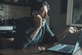 Mature young man working at home in the kitchen using laptop and calling with mobile phone. Concept of alternative workplace and Royalty Free Stock Photo