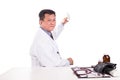 Matured Asian medical practitioner holding medicine seated behind desk