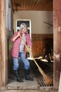 Matured farm woman sweeping the stable