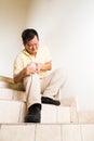 Matured man suffering acute knee joint pain seated on stairs Royalty Free Stock Photo