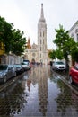 Matyas-templom, Matthias Church from SzenthÃÂ¡romsÃÂ¡g street, with tower reflection on wet pavement