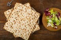 Matzah on a plate and maror on a wooden Passover board next to Magen David on a chain.