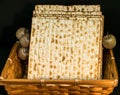 Matzot in a wicker basket with souvenir apples and roses on black background. Pesach-Jewish easter.