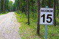 A maximum 15 speed limit sign along a gravel road