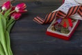 9 May background - George ribbon, red flowers front-line letters, military cap and orders on the wooden background. Victory day or Royalty Free Stock Photo