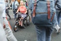 Senior woman on a disability scooter bike or wheelchair crossing busy city street with crowds of