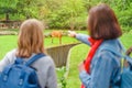 Two girls friends students zoologist with backpacks watch an antelope at a zoo or on a safari