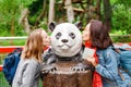 Two young happy girls kissing a wooden giant panda statue in Berlin Zoo