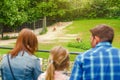 Young family of mother, daughter and father watching kangaroo herd in zoo or safari park