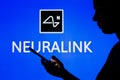 May 2, 2022, Brazil. In this photo illustration, the Neuralink logo is seen in the background of a silhouetted woman holding a
