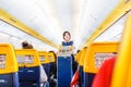 Interior of Ryaniar airplane with passengers on seats and stewardess in uniform walking the aisle