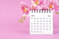 The May 2023 calendar desk and pink orchid on pink background