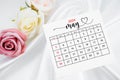 The May 2024 calendar page and rose flower on white satin textile background Royalty Free Stock Photo