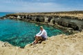 A man sits on a ledge of rock above the sea at Cape Greco . Royalty Free Stock Photo