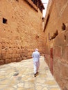 Bedouin man in a turban and white robe walks between the walls of St. Catherine\'s Monastery on Mount Sina