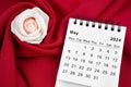 May 2024 desk calendar and pink rose on red textile Royalty Free Stock Photo