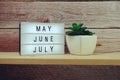 May, June, July word in light box on wooden background