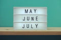 May, June, July word in light box on wooden shelves background