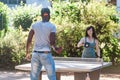 multiracial couple playing ping pong table tennis outdoors