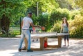 multiracial couple playing ping pong table tennis outdoors