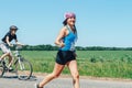 May 26-27, 2018 Naliboki,Belarus All-Belarusian amateur marathon Naliboki A woman runs alongside a cyclist on the road