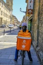 May 2021 Parma, Italy: Courier on bike with special orange backpack with Just eat logo icon close-up on city street. Food delivery