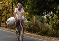 01 May 2022, Prayagraj Uttapradesh. An old Indian farmer carrying grass in a sack on his bicycle to feed his cattle