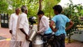 An Indian man pouring out milk to milkman. Milk man measuring the milk with Liter cane