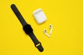 May 01, 2020, Rostov, Russia: Black AppleWatch and white AirPods with box on bright yellow background. Indoors, isolated, copy Royalty Free Stock Photo