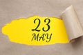 may 23. 23th day of the month, calendar date. Hole in paper with edges torn off. Yellow background is visible through