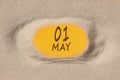 May 1. 1th day of the month, calendar date. Hole in sand. Yellow background is visible through hole