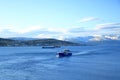 May 28 2022 - Tromso, Norway: Ships approach the port, Snowy mountains in the background Royalty Free Stock Photo