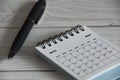 May 2023 white desk calendar with black pen on wooden table.