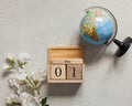 May 1 on a wooden calendar, next to a white flower and a globe. International Day of Workers` Solidarity. Space text. Royalty Free Stock Photo