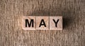 MAY is a word written on wooden cubes. On a brown background for your design, top view Royalty Free Stock Photo