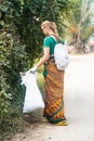 Mayapur, West Bengal, India - Dec 14, 2019. female volunteer collects garbage in India with recycle project outside.