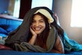 Maybe its time to do some laundry. Portrait of a happy young woman lying under a pile of clothes on her bed. Royalty Free Stock Photo